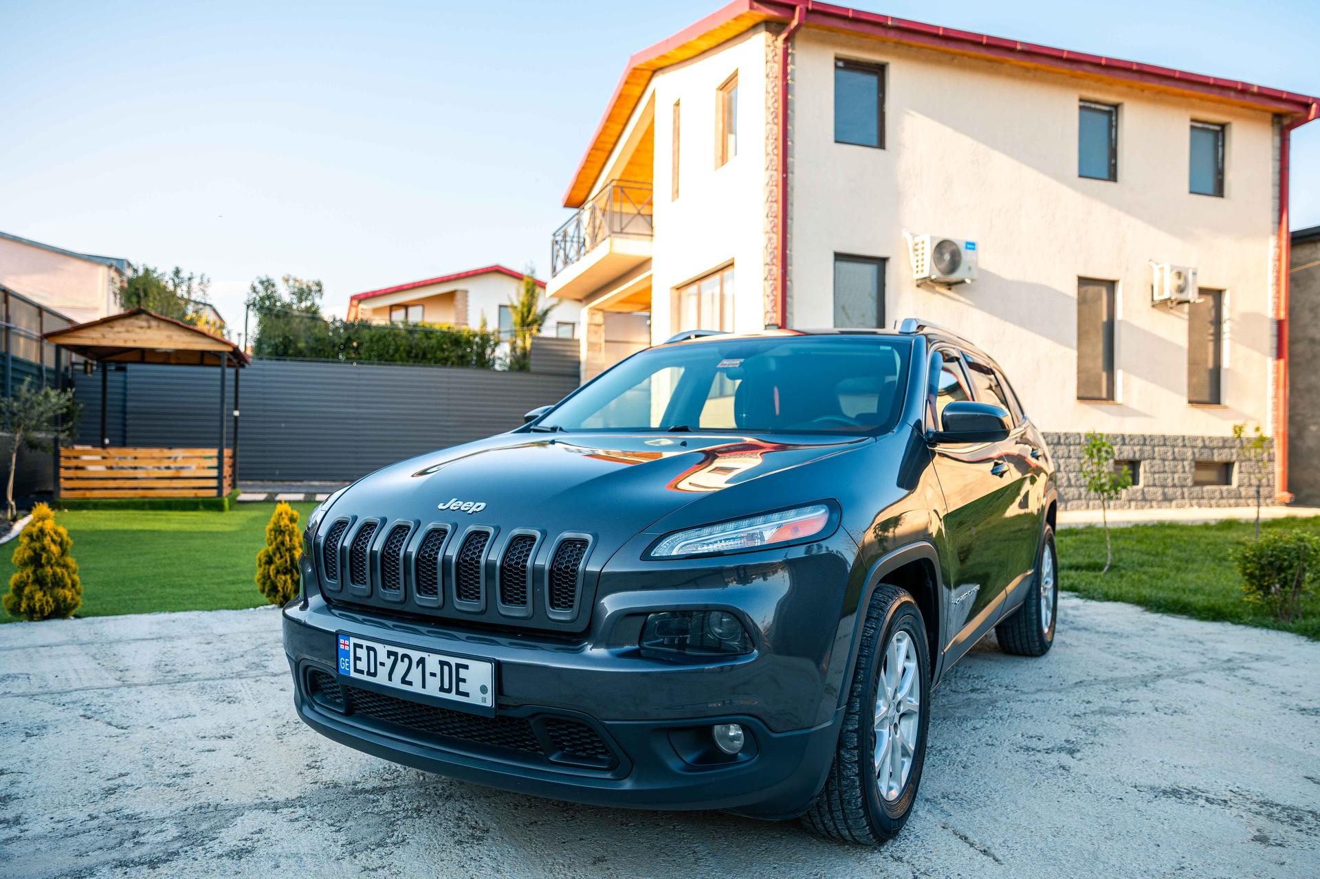 Dunkeltürkiser Jeep Cherokee 2017, Miet-SUV vor einem Haus